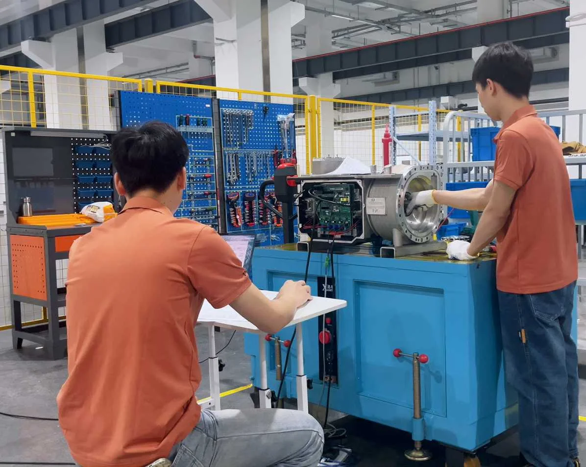 Technicians working beside an open compressor on an engineering bench